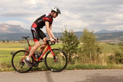 Cycliste sur un vélo de route CBT ITALIA rouge équipé d'un kit moteur Ultra dans la roue arrière et batterie TESLA en inox sur le cadre.
