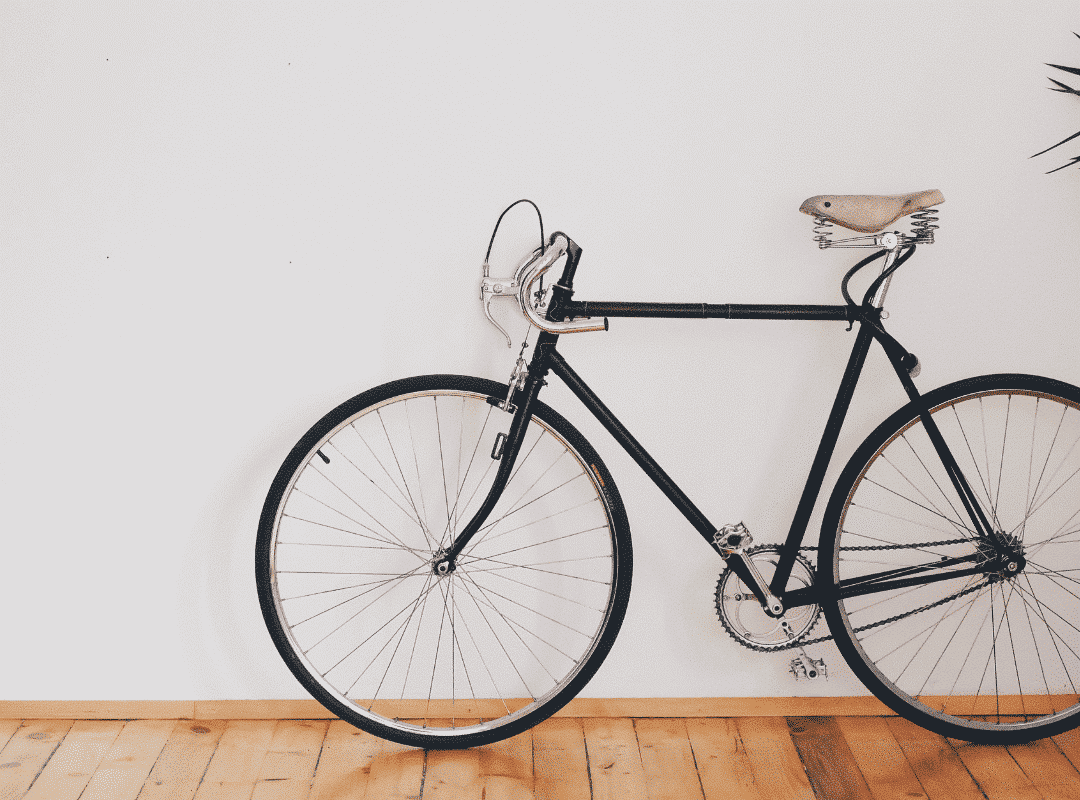 Zwarte vintage fiets leunend op een witte muur met parketvloer