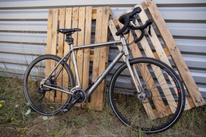 Annad Gravel bike in titanium op een houten basis uitgerust met een elektrificatie kit bestaande uit een motor met een interne batterij geplaatst in de naaf van het achterwiel.